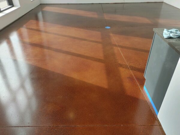 Grind & Stain- Orange_ Walnut Polished concrete floor stained orange and walnut tones showing smooth semi-gloss finish.
