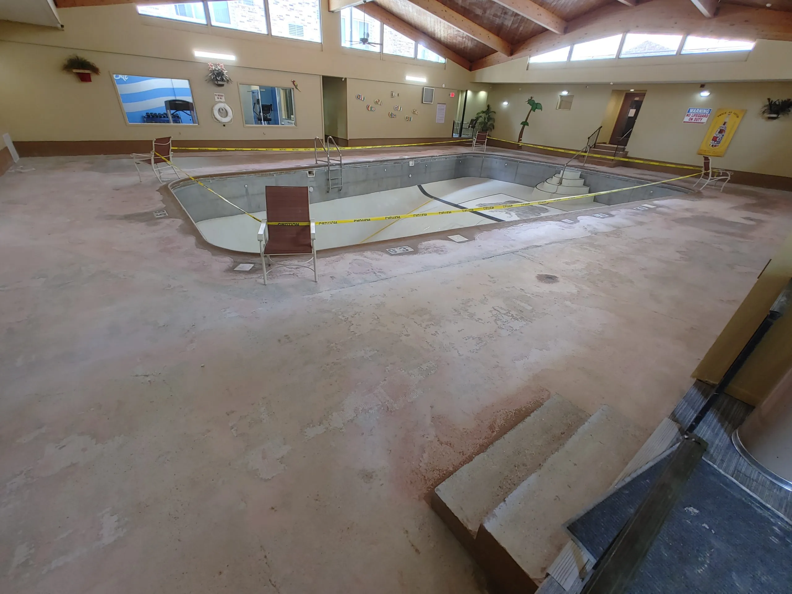 #1 Chairs holding caution tape around a pool, suggesting concrete servicing is about to start happening.